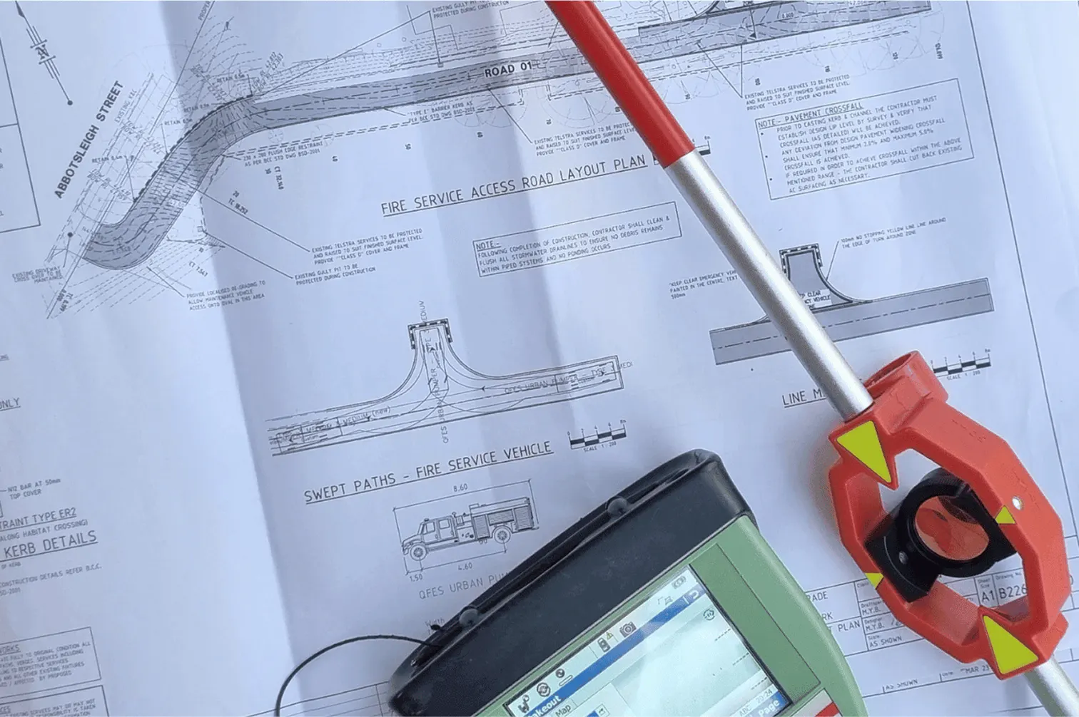 Survey prism pole and field controller on a printed site layout plan