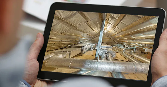 Inspector reviewing a 360 image of a ceiling void and ductwork on a tablet